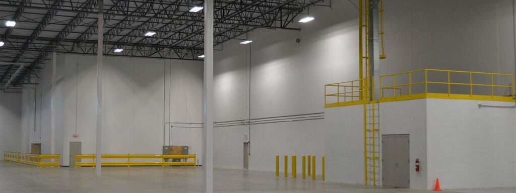 Warehouse interior with high ceilings, concrete floor, and yellow safety railings.