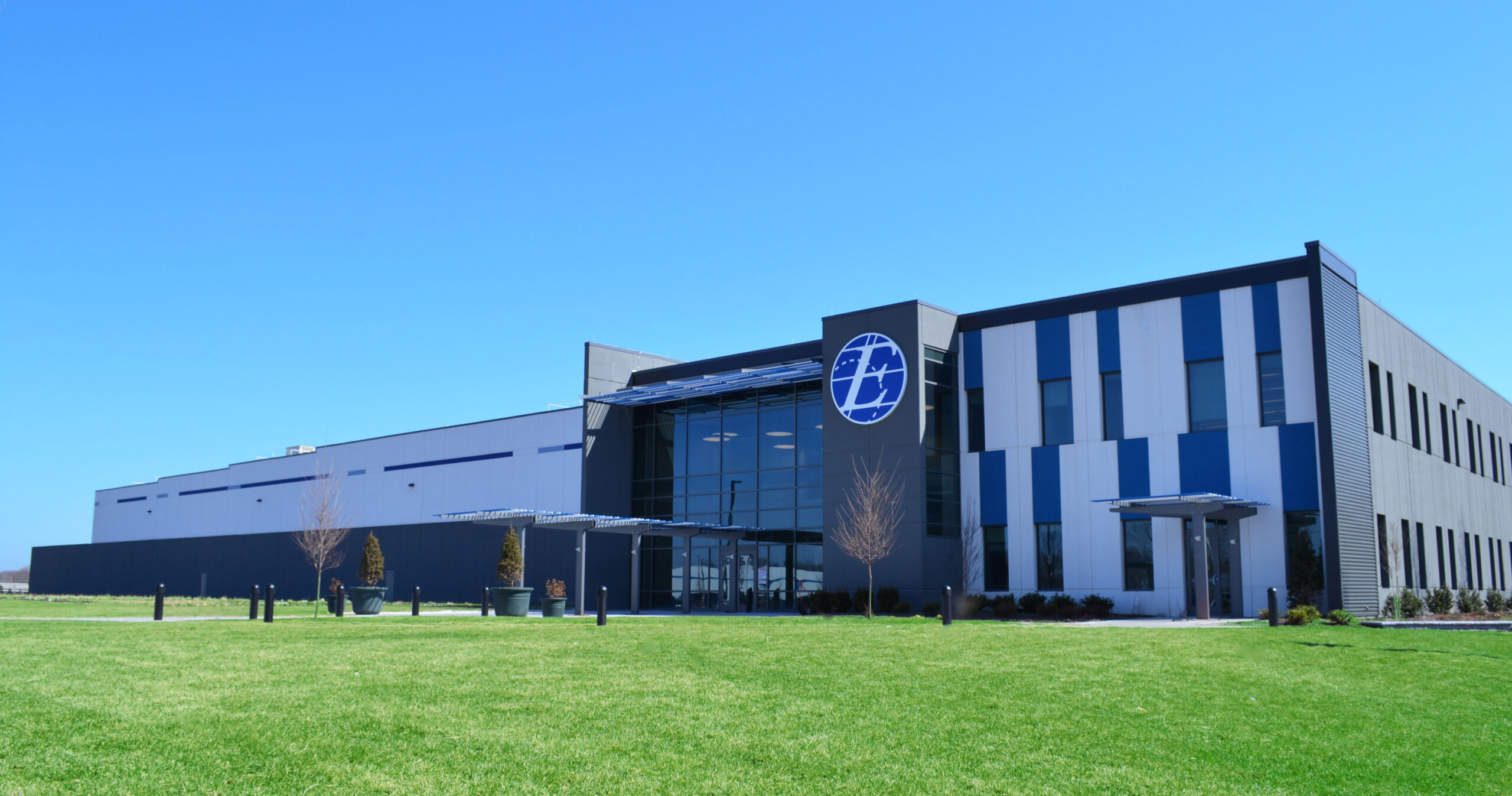 NFI Express Scripts building project with modern architecture, blue and white facade, and green lawn under a clear sky.